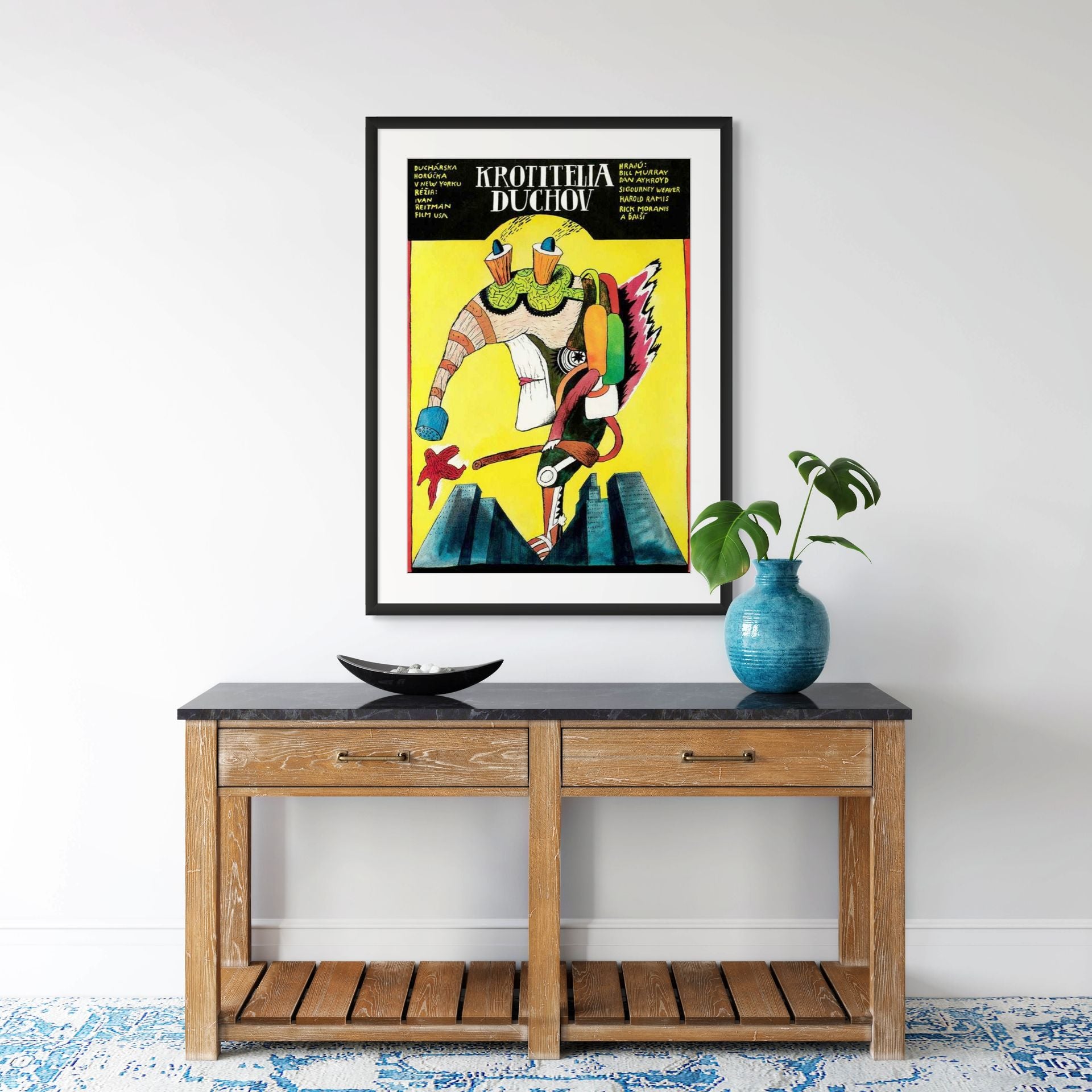 Framed colorful poster on a wall above a wooden console table with decorative items.
